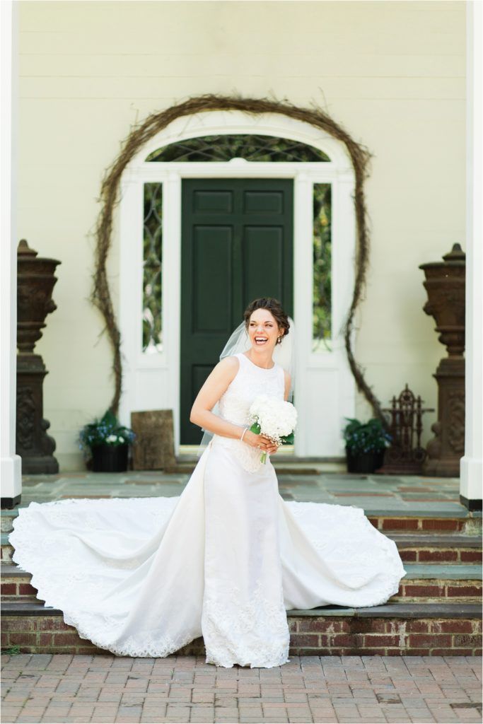 Elegant white wedding dress with flowing train against an arched doorway entrance.