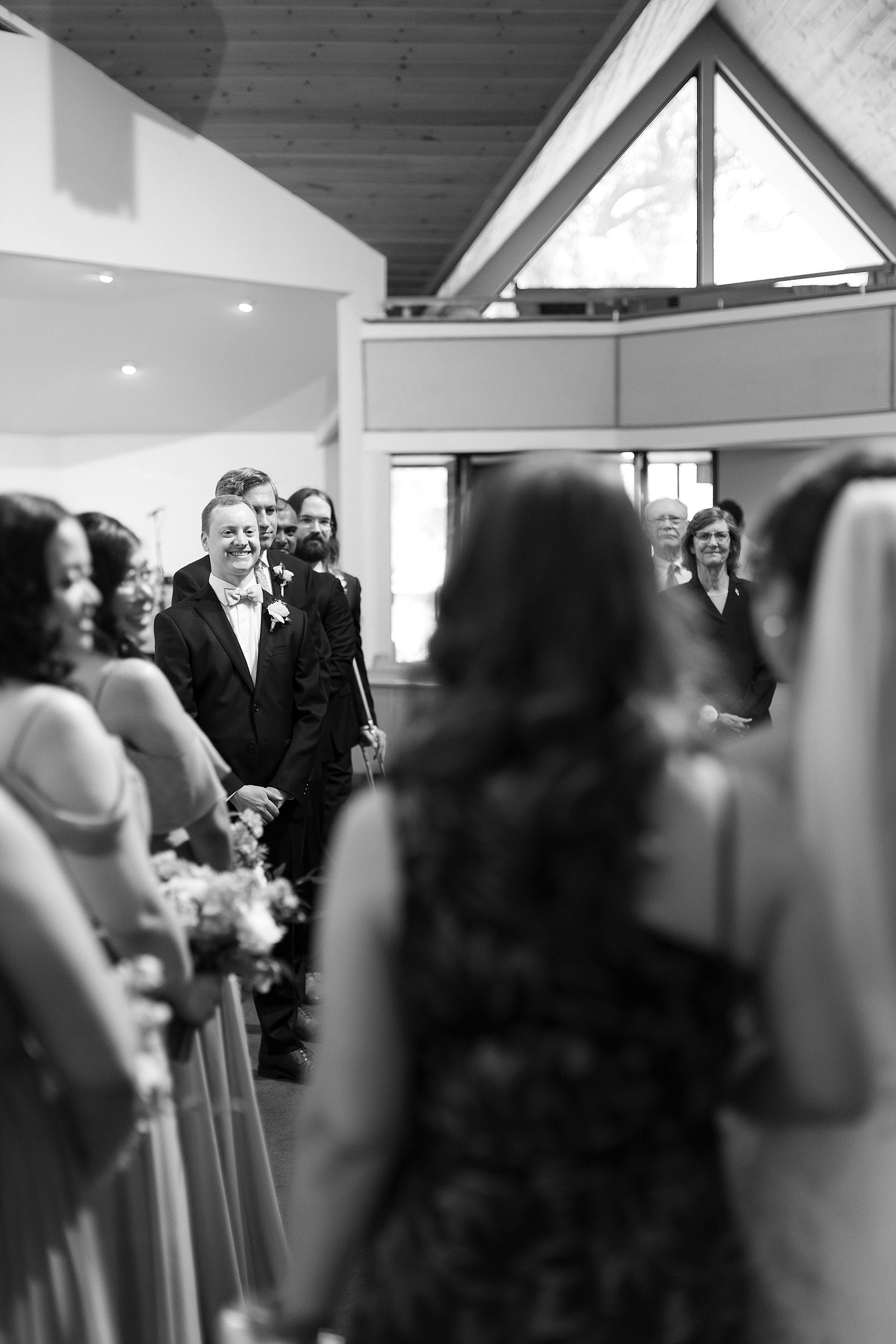 Black and white photo captures processional moment during church wedding ceremony.