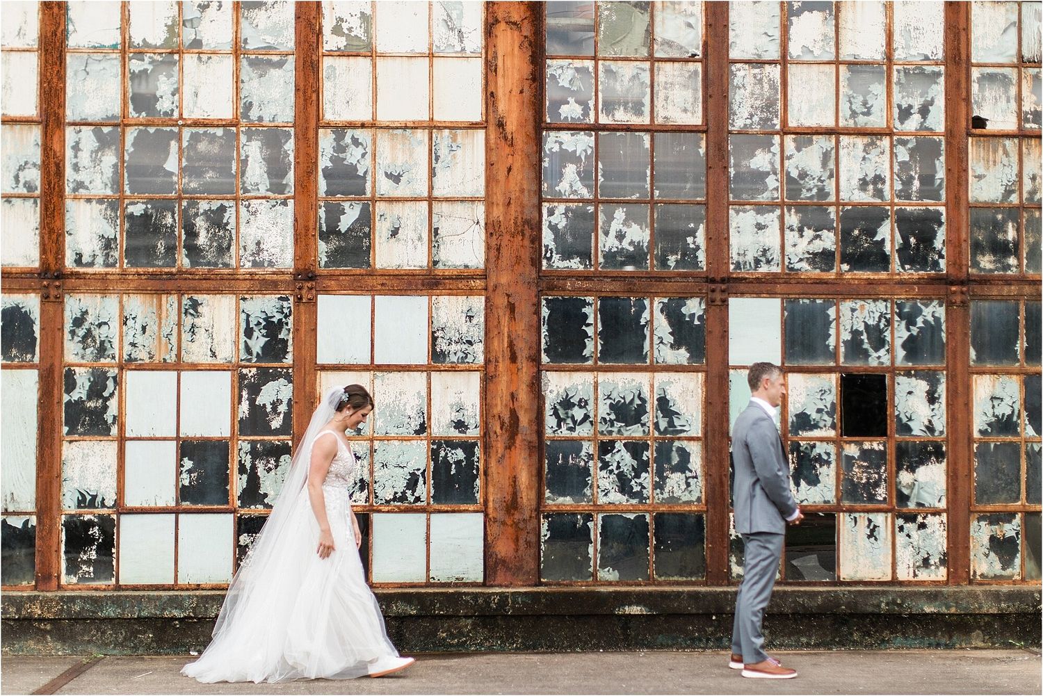 Wedding couple posing in front of rustic industrial windows with distressed paint.
