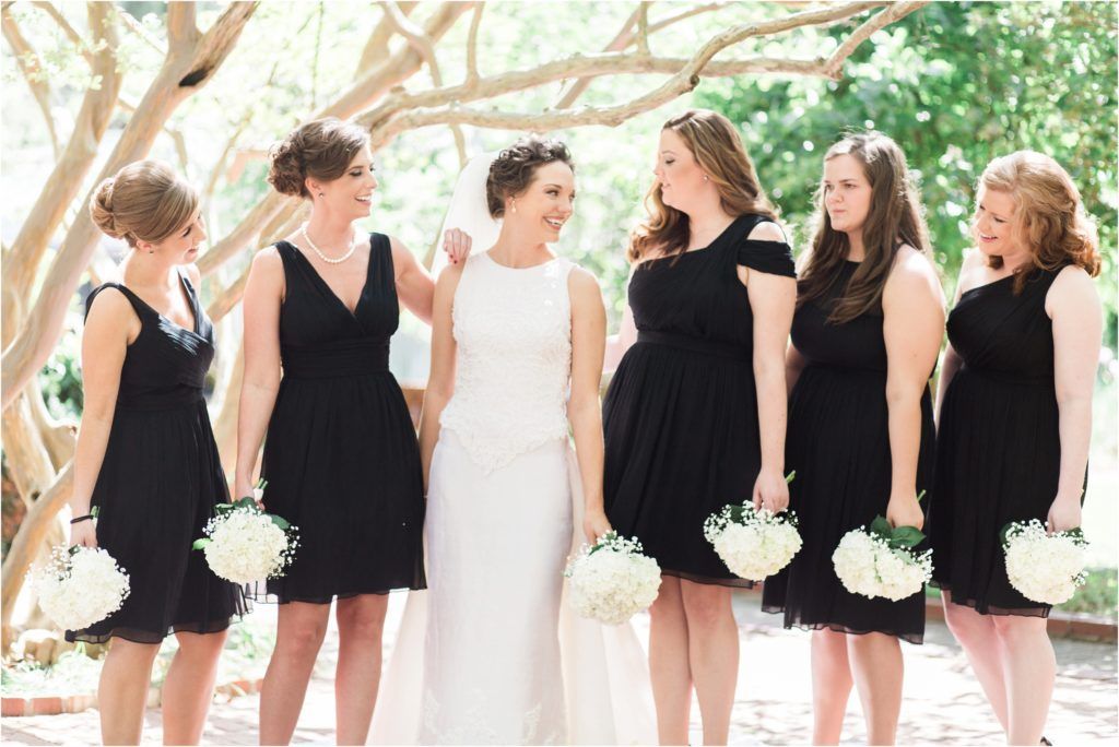 Wedding party in black and white attire holding bouquets outdoors.