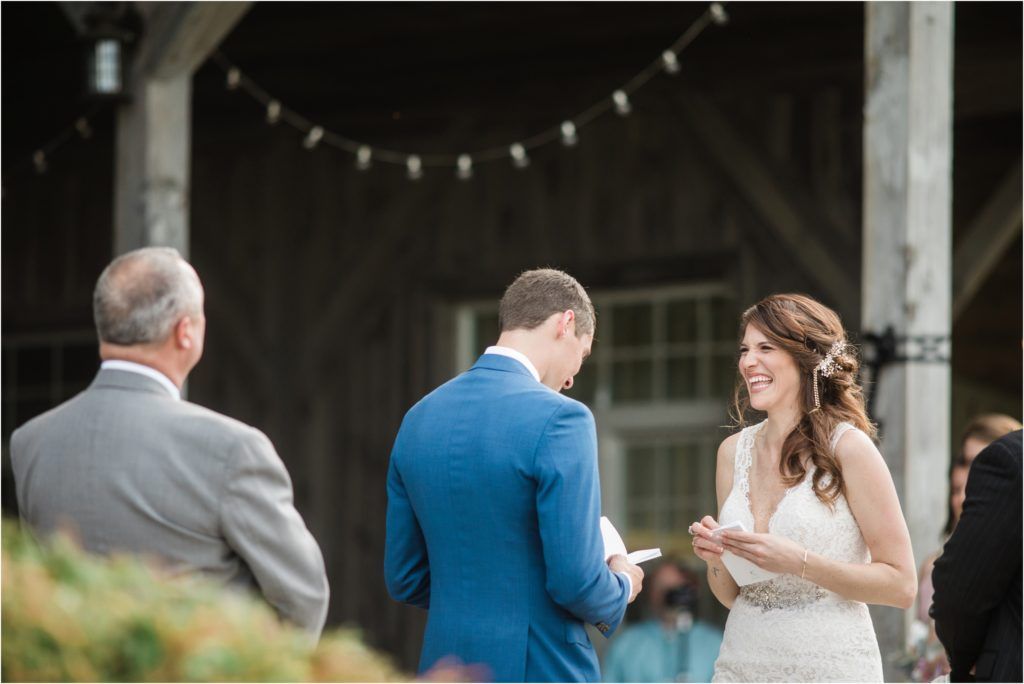 An intimate wedding ceremony exchange beneath string lights in a rustic outdoor pavilion setting.