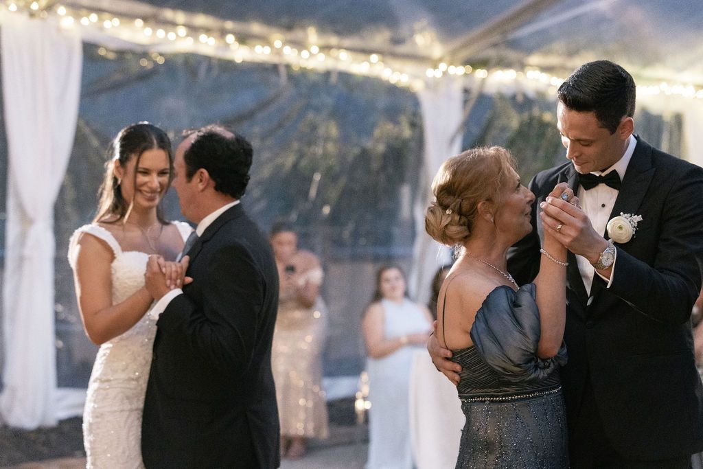 Wedding reception dance floor with multiple couples dancing under string lights.