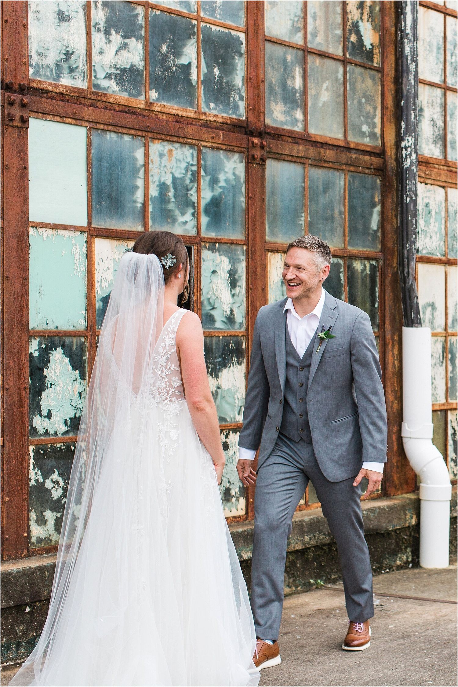 Wedding couple sharing a moment against distressed industrial windows.