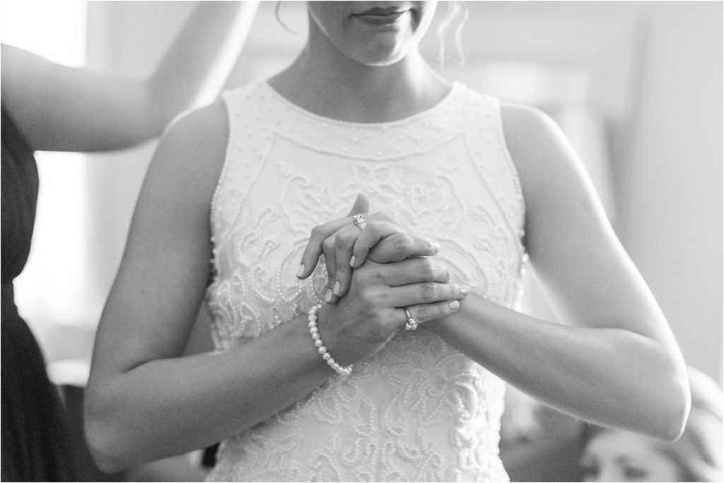 Close-up of hands wearing a delicate bracelet and white lace dress details.