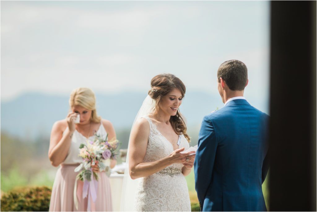 An emotional moment during an outdoor wedding ceremony with mountains visible in the background.