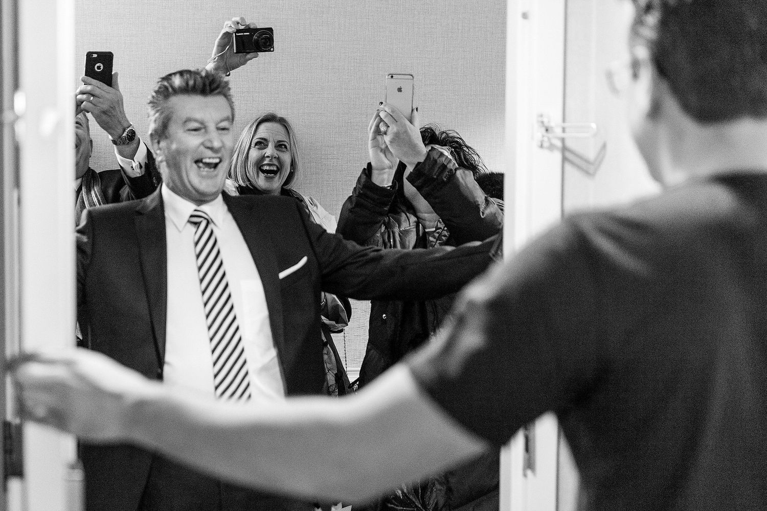 Candid black and white photo of celebratory moments being captured on smartphones.