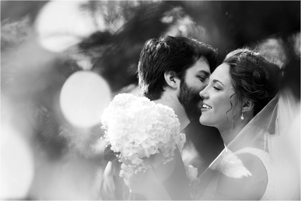Intimate black and white portrait of tender wedding moment with bokeh light effects.