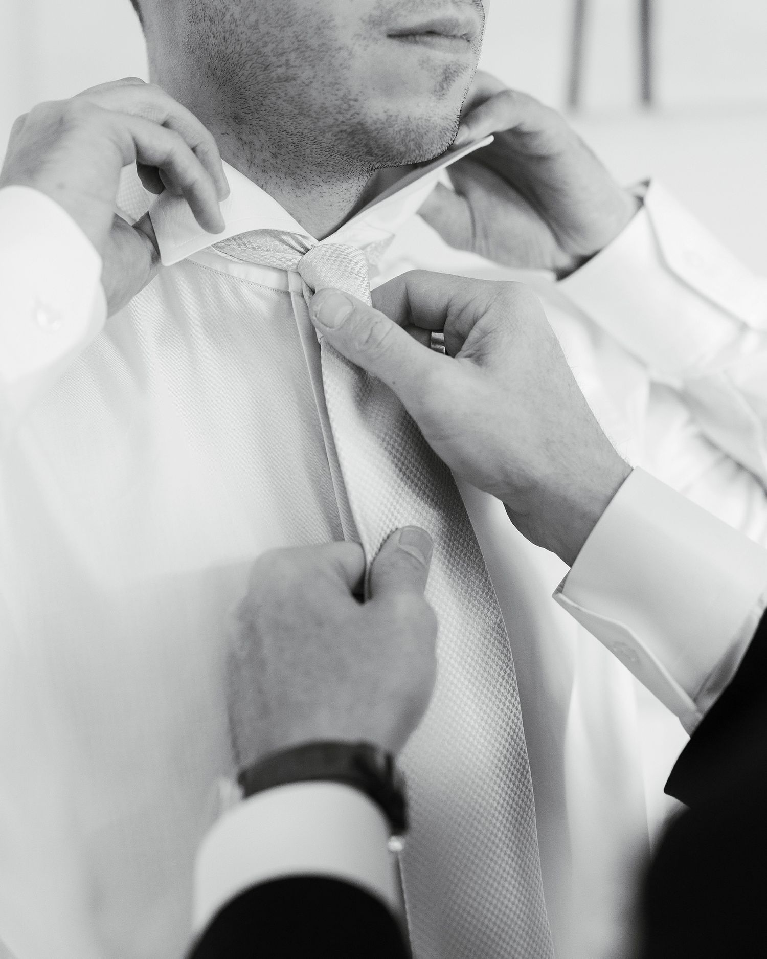 Close-up sequence showing the process of adjusting a white tie and collar for a formal occasion.