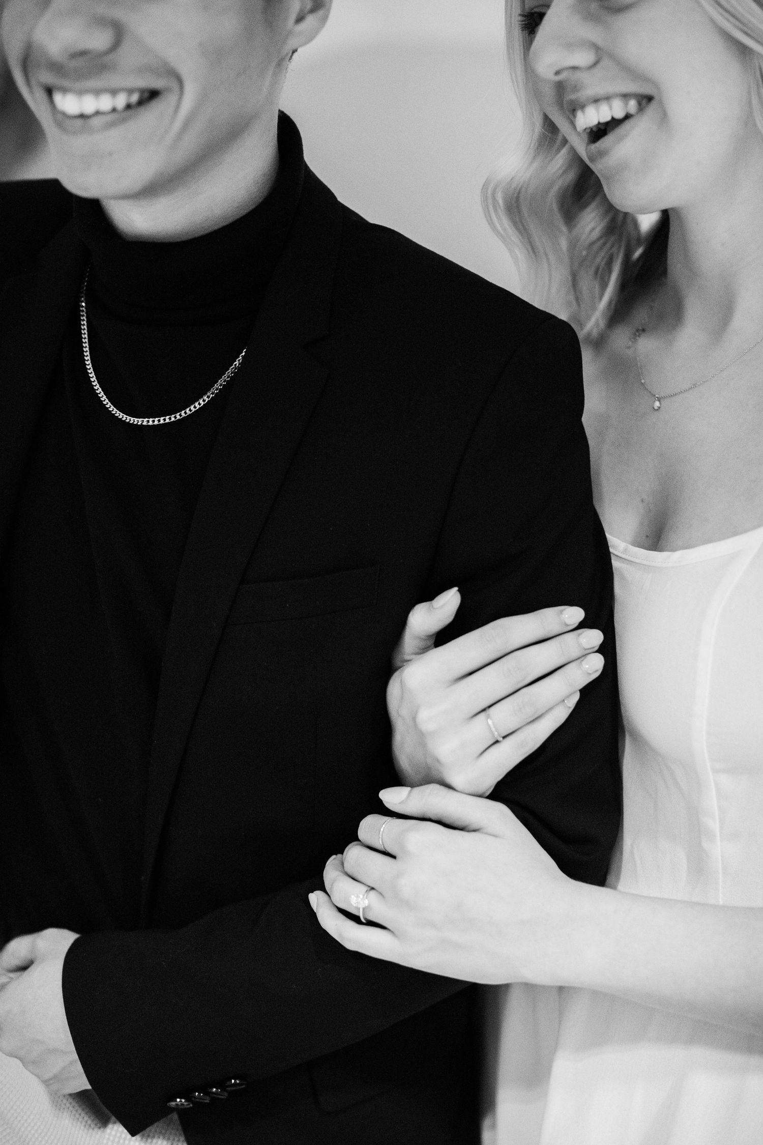 Black and white engagement photo detailing couple's hands and smiles