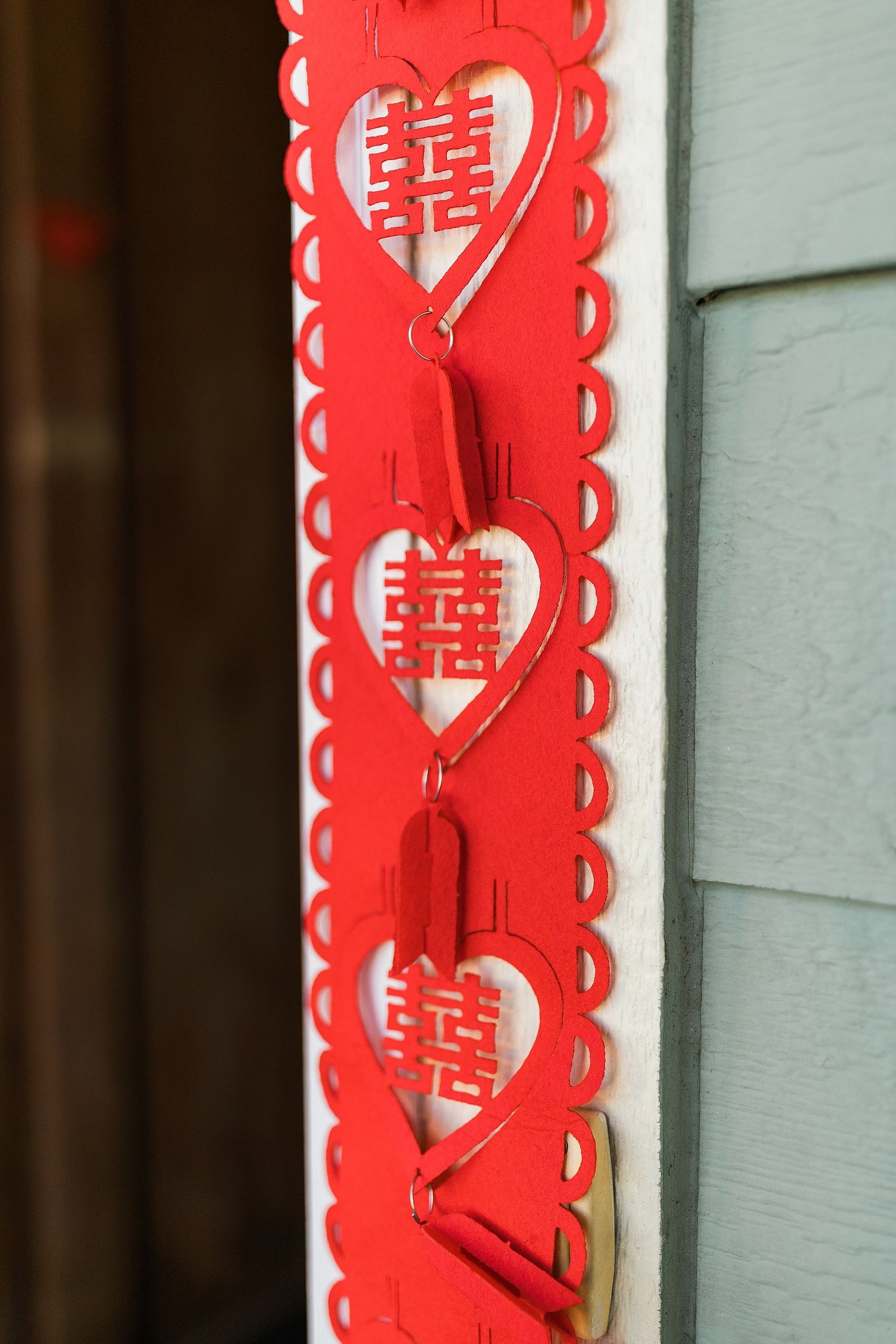 Red paper decoration with Chinese double happiness symbols in heart shapes and scalloped edges creates festive border.