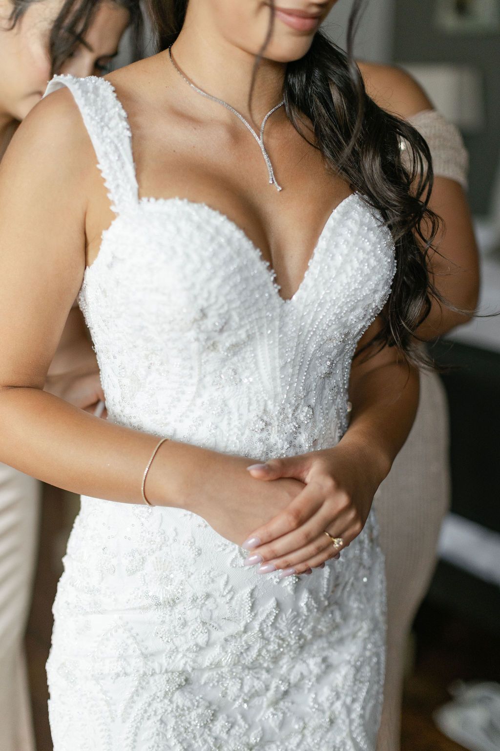 Bride getting into wedding dress with help of bridesmaids