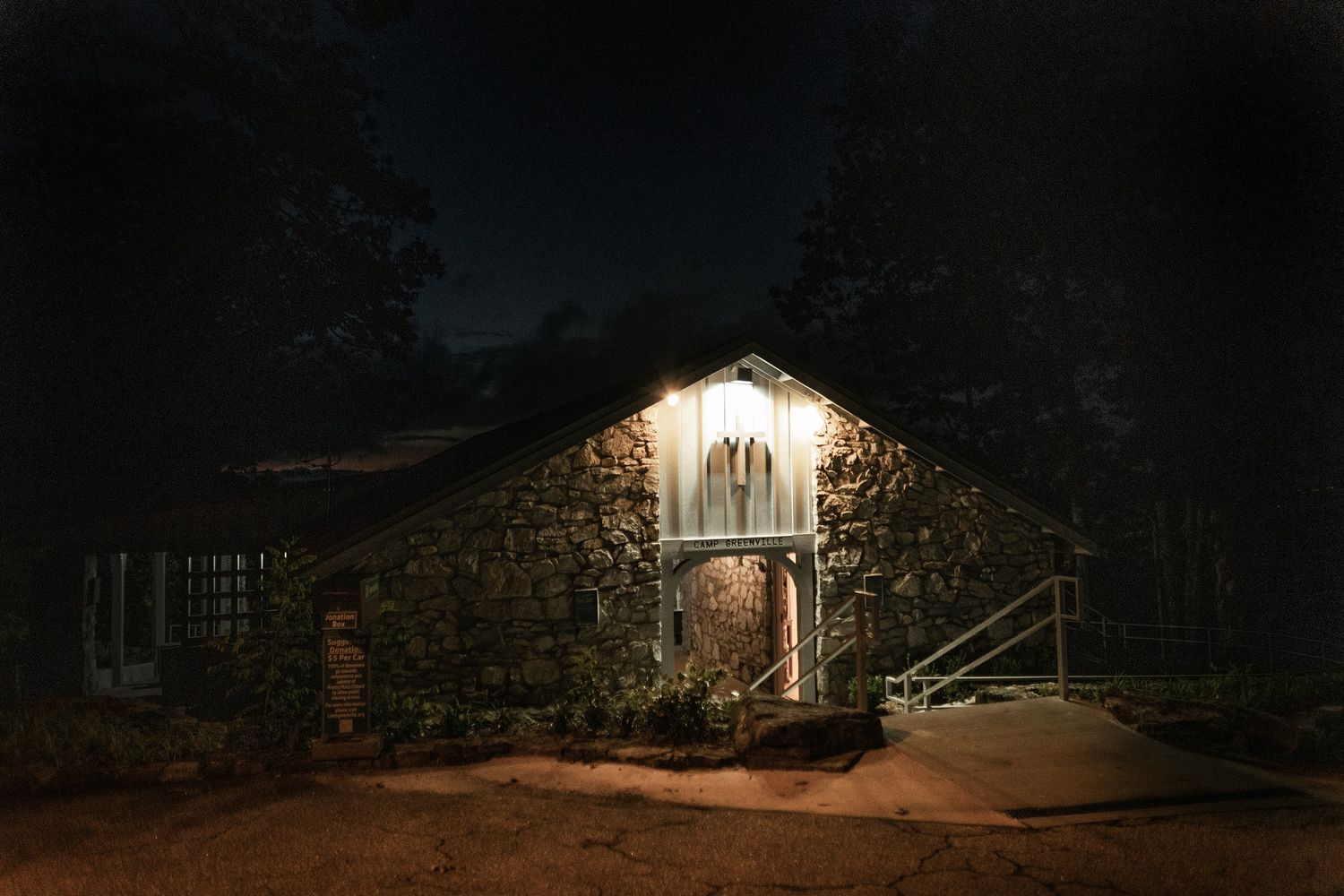 A stone cellar entrance illuminated by a single light glows warmly against the dark night.