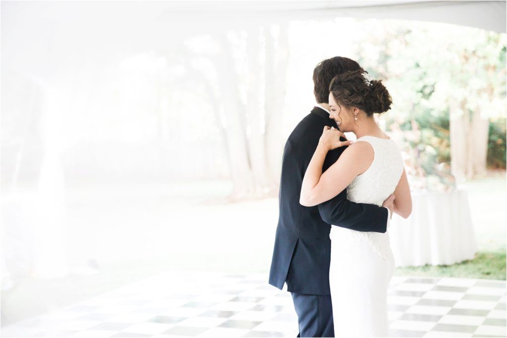 A tender moment captured during a wedding dance under a white tent.
