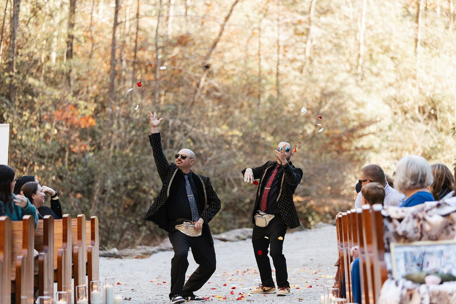 A joyful candid moment between wedding officiants and guests during outdoor autumn ceremony in the woods.