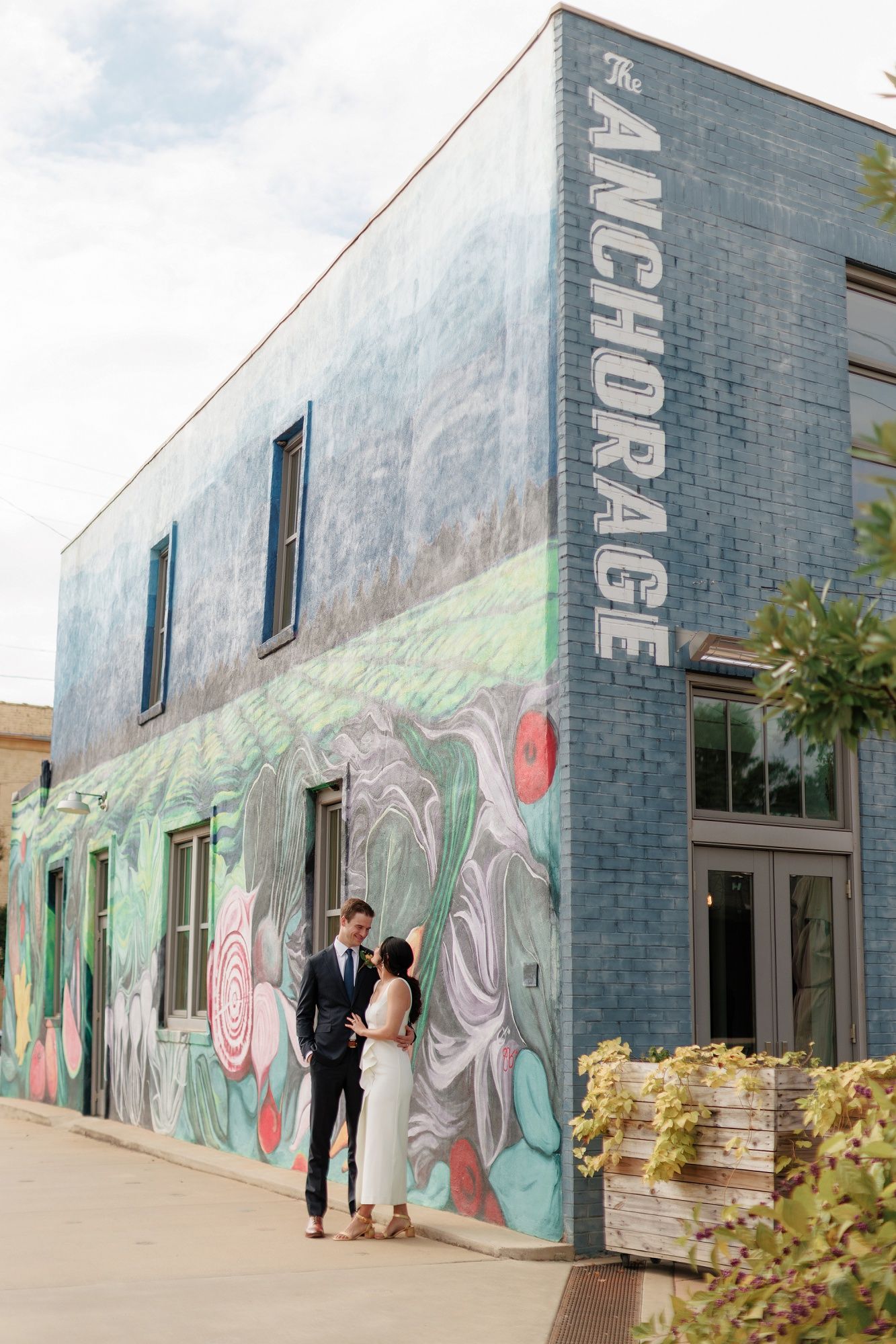 A series of photos showing a modern building exterior with colorful graffiti murals and people walking alongside the wall.