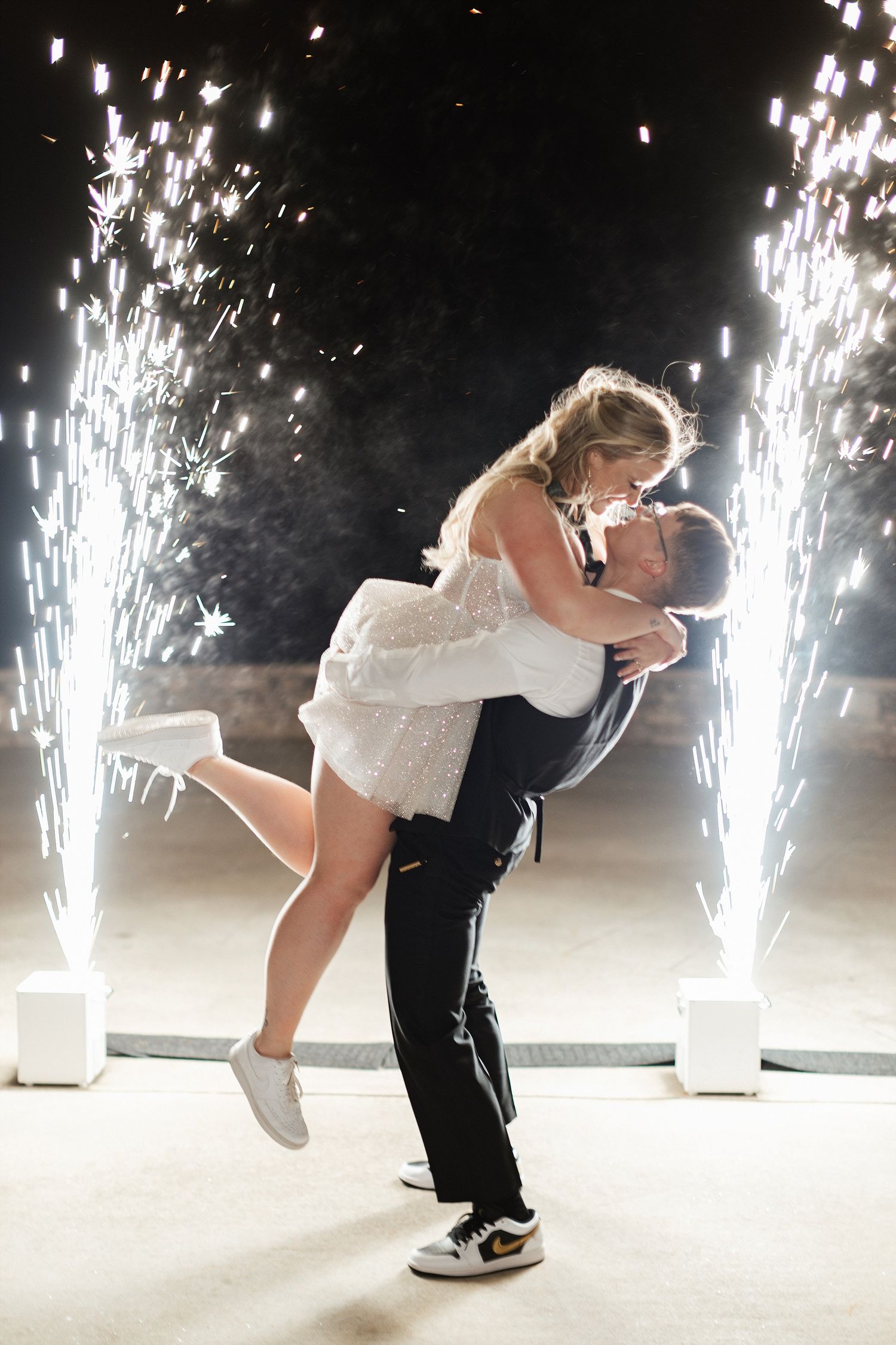 Couple shares romantic dance with sparkler fountains creating magical light effects in the background.