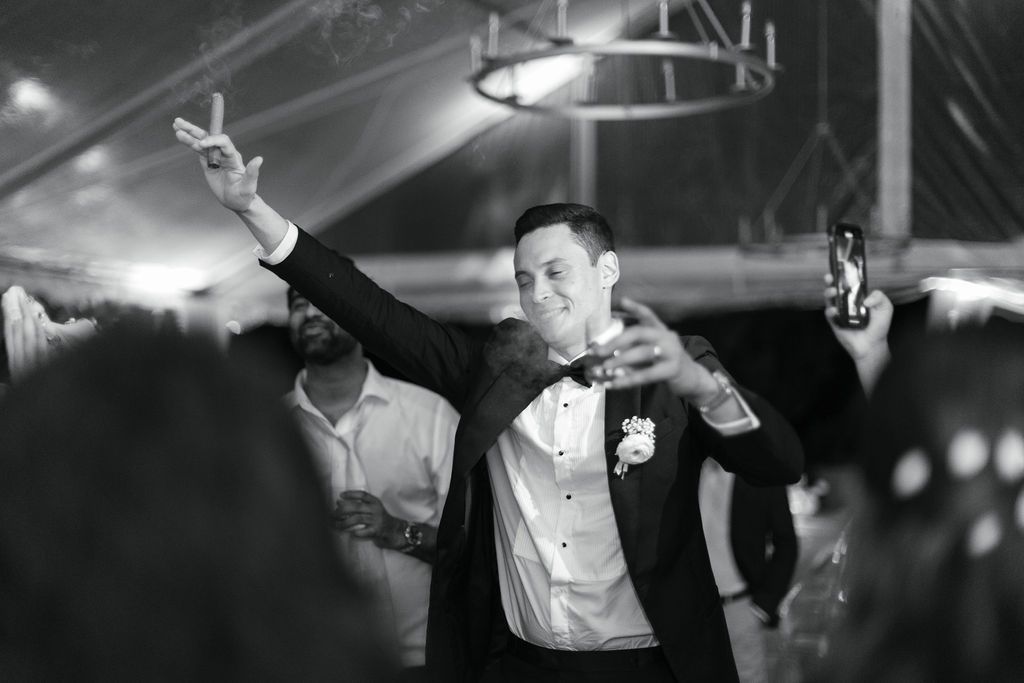 A monochrome shot of someone gesturing enthusiastically during a wedding celebration.