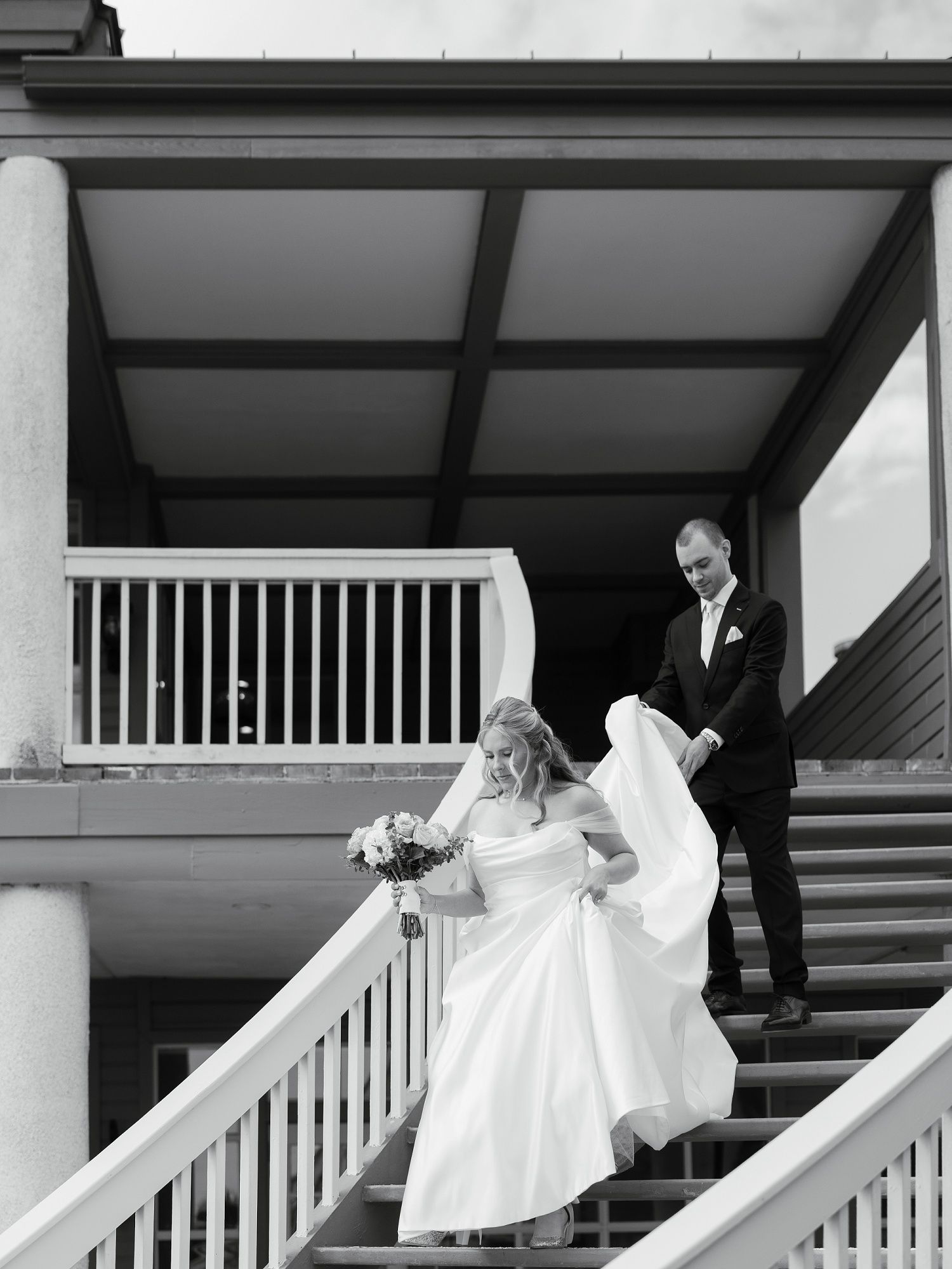 Wedding party posing on a white columned porch with classic architectural details.