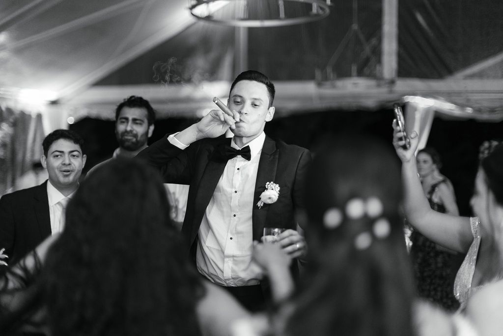 A black and white photo of guests dancing and celebrating at an elegant wedding reception.