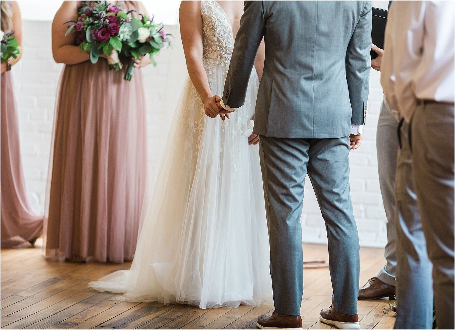 Wedding party stands at altar with bridesmaids in mauve dresses holding purple bouquets.