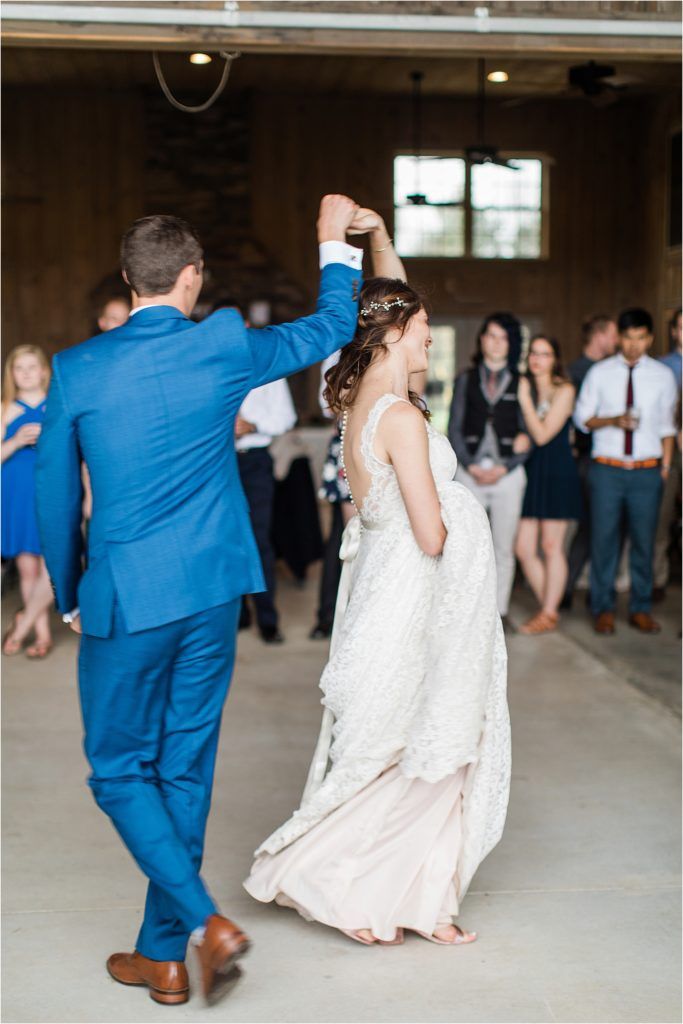Dancing couple in blue suit and white dress during wedding celebration.