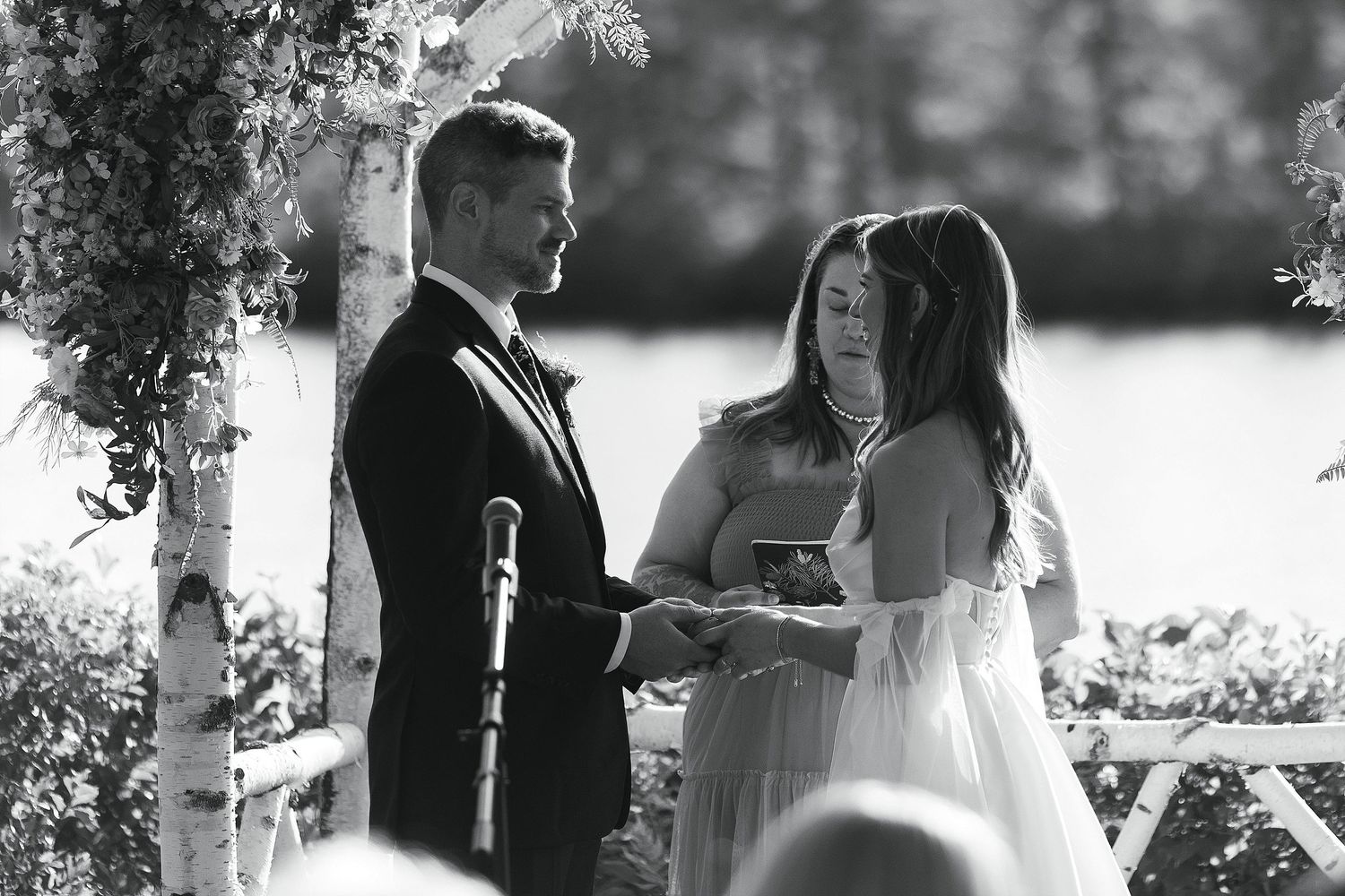 An intimate black and white moment captured during an outdoor wedding ceremony.