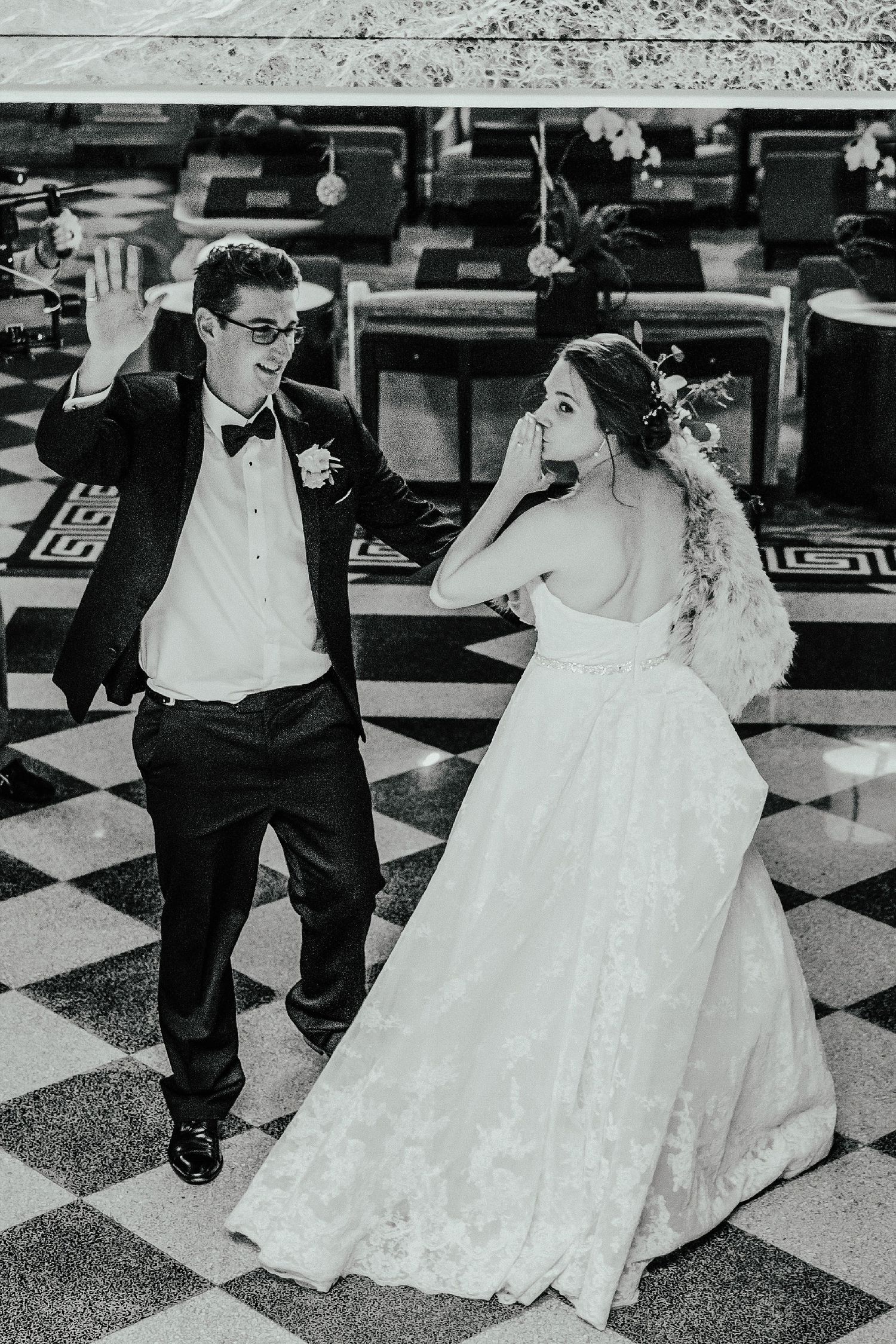 Black and white photo of newlyweds dancing on a checkered floor.