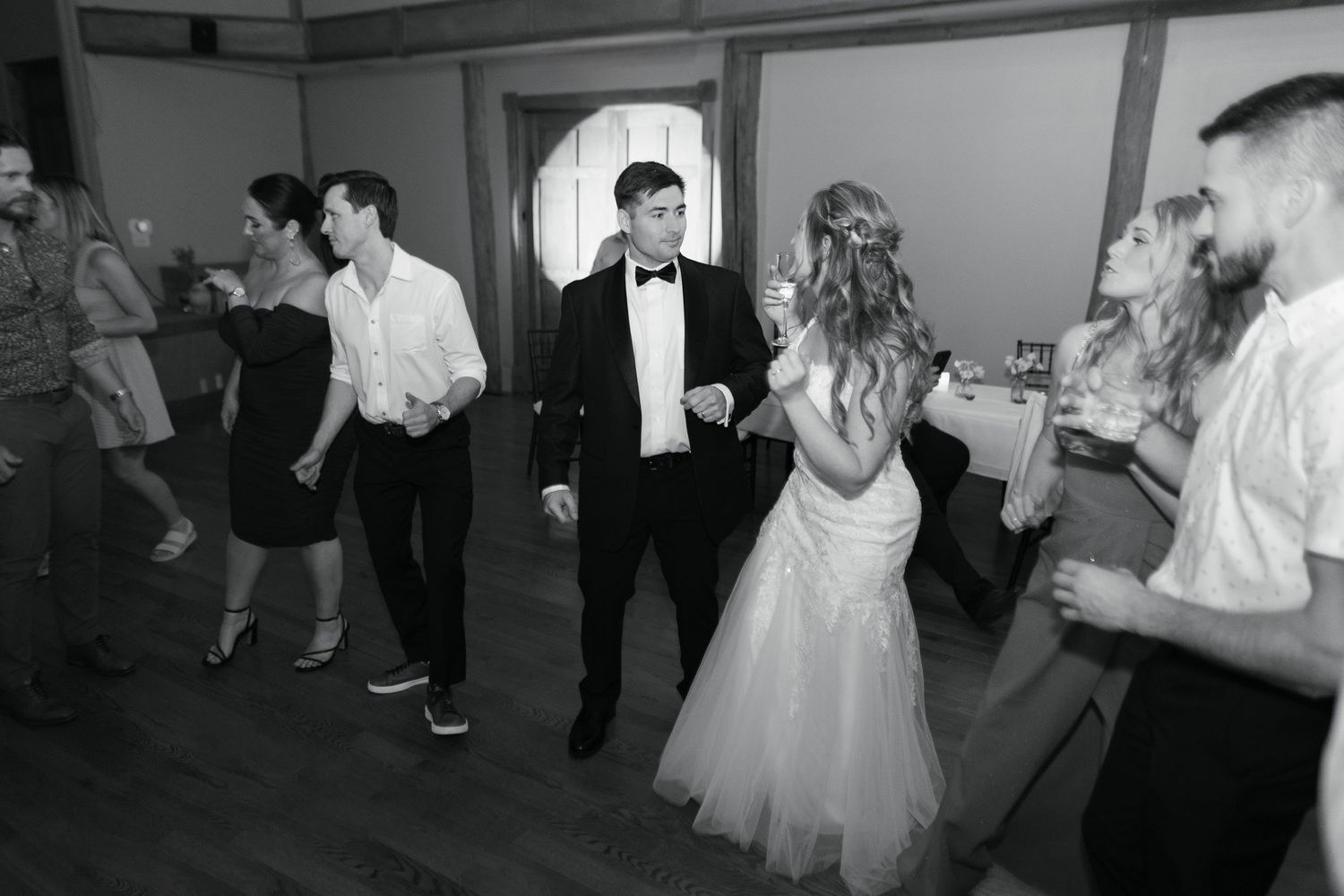 People dancing and enjoying themselves at a formal event with men in suits and women in elegant dresses.