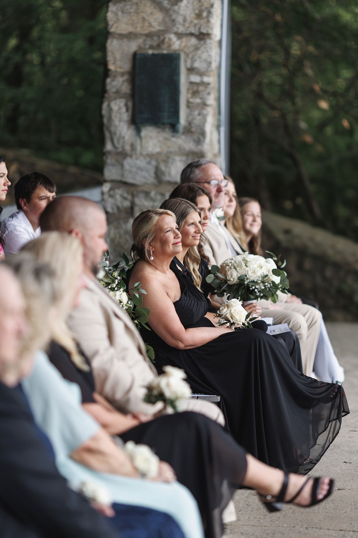 Wedding guests seated outdoors enjoying the ceremony with joyful expressions.