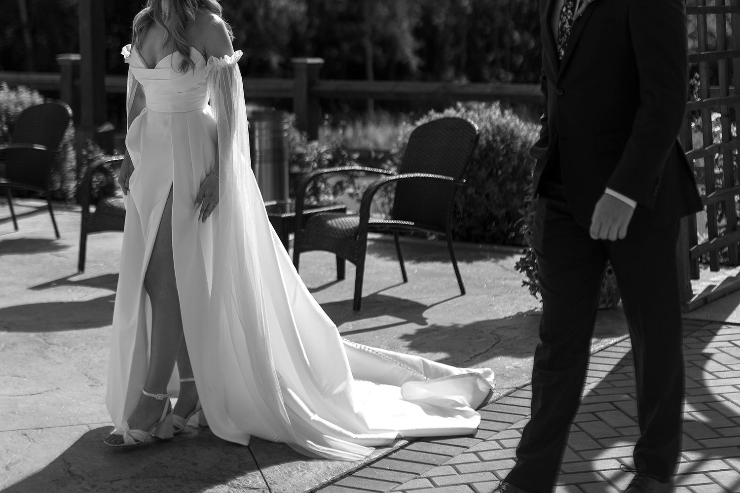 Black and white photo of wedding dress train flowing across outdoor patio.