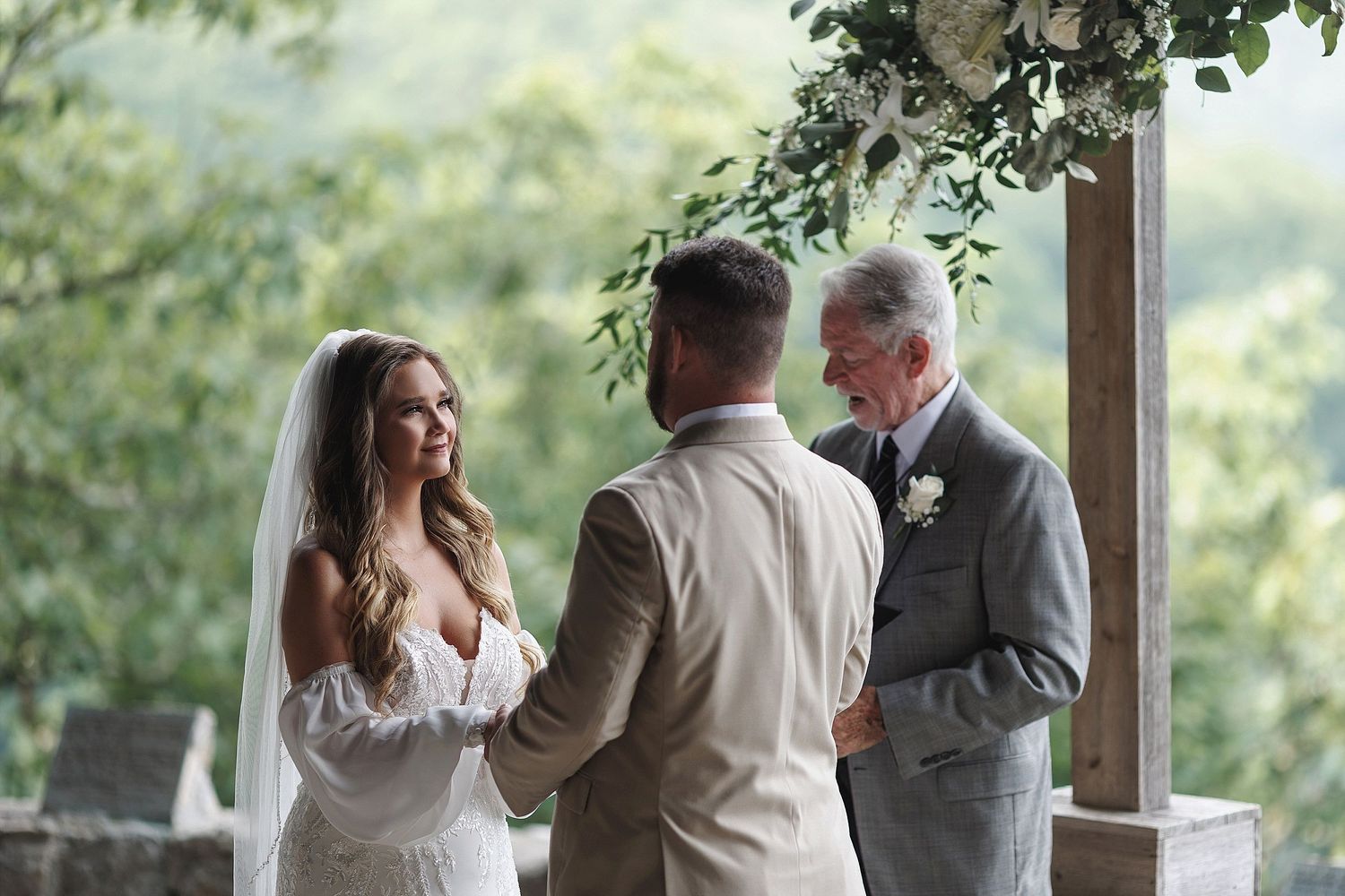 Wedding ceremony under a covered pavilion with mountain views in the background.