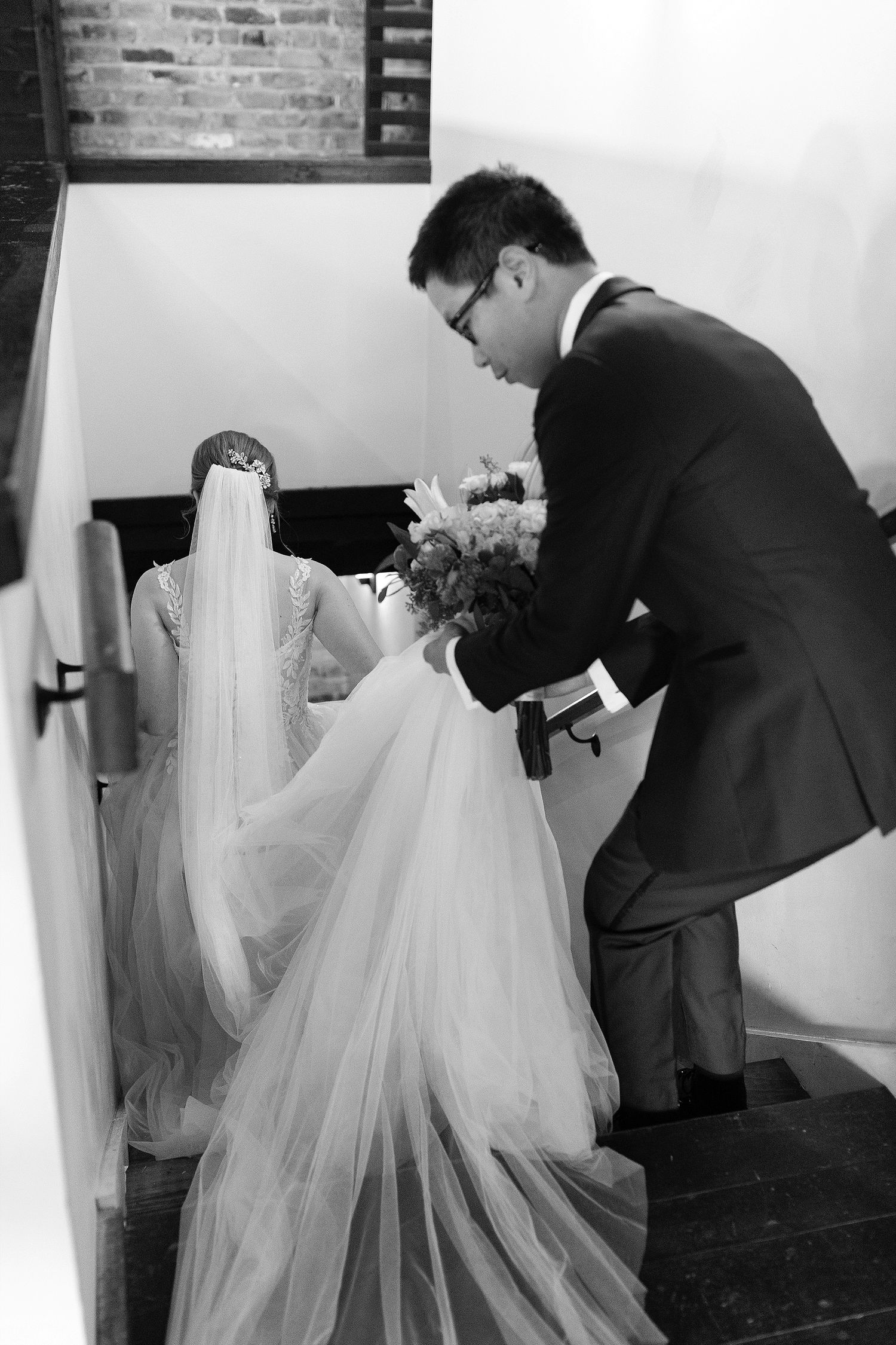 A black and white wedding photo captures a tender moment as a couple shares time together on their special day.