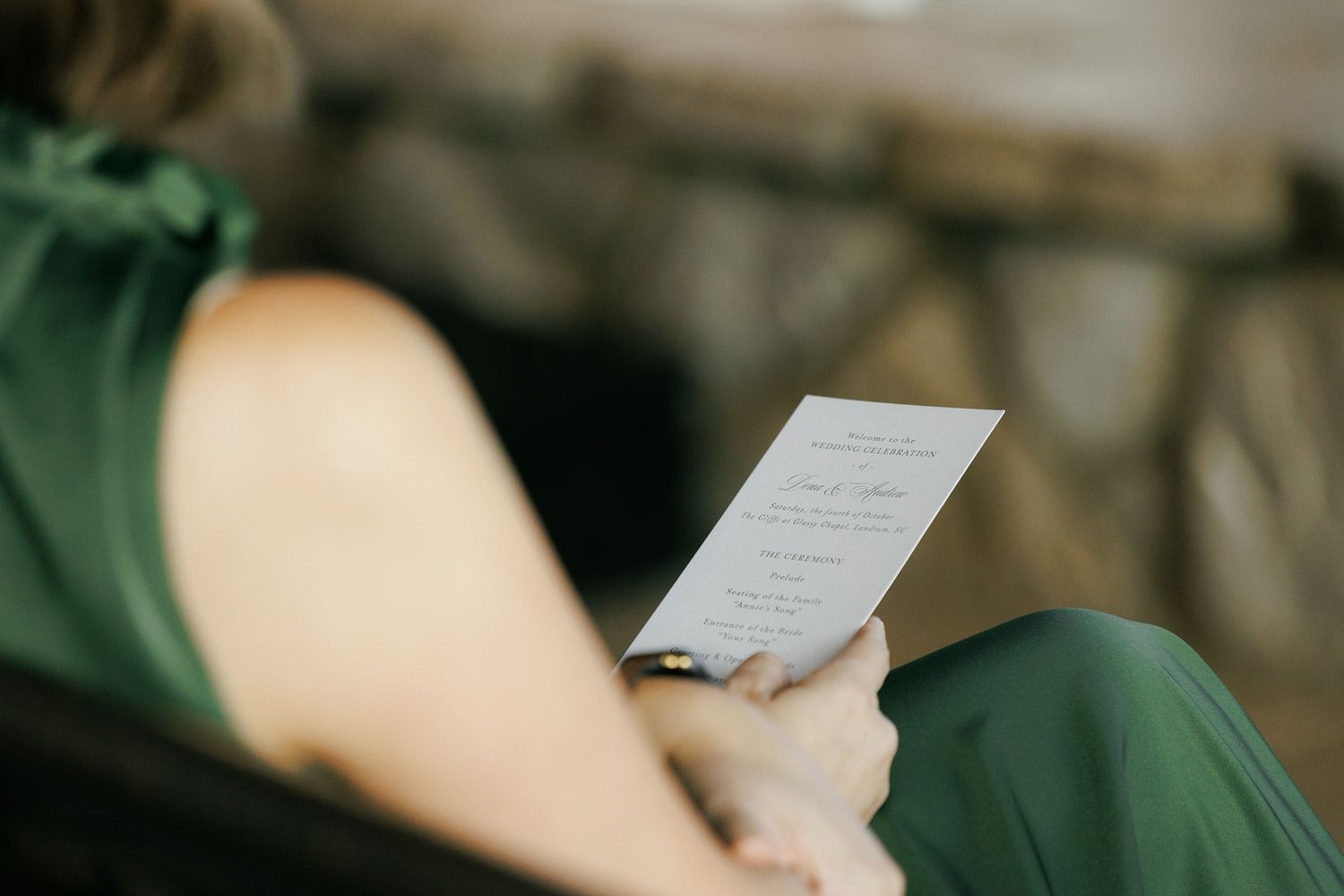 Person reading a white paper document in a dimly lit setting with blurred background details.