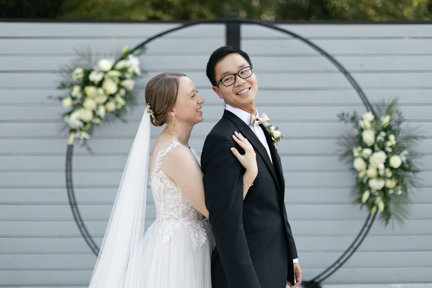 Newlyweds holding hands while running across a crosswalk in an urban setting with high-rise buildings.