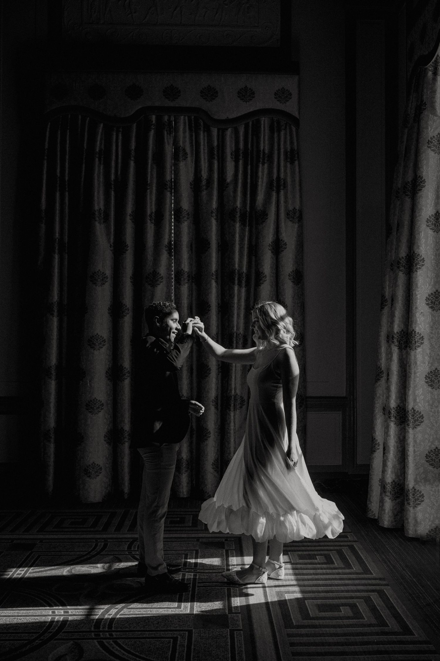 A couple dances in a beam of sunlight during their Westin Poinsett Engagement session
