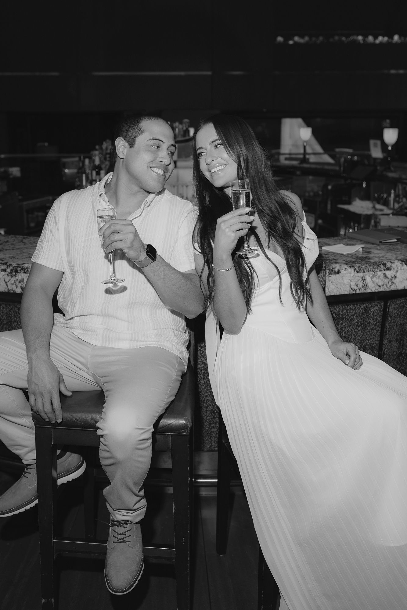 Black and white candid photos show a couple sharing intimate moments at a celebration with wine glasses.