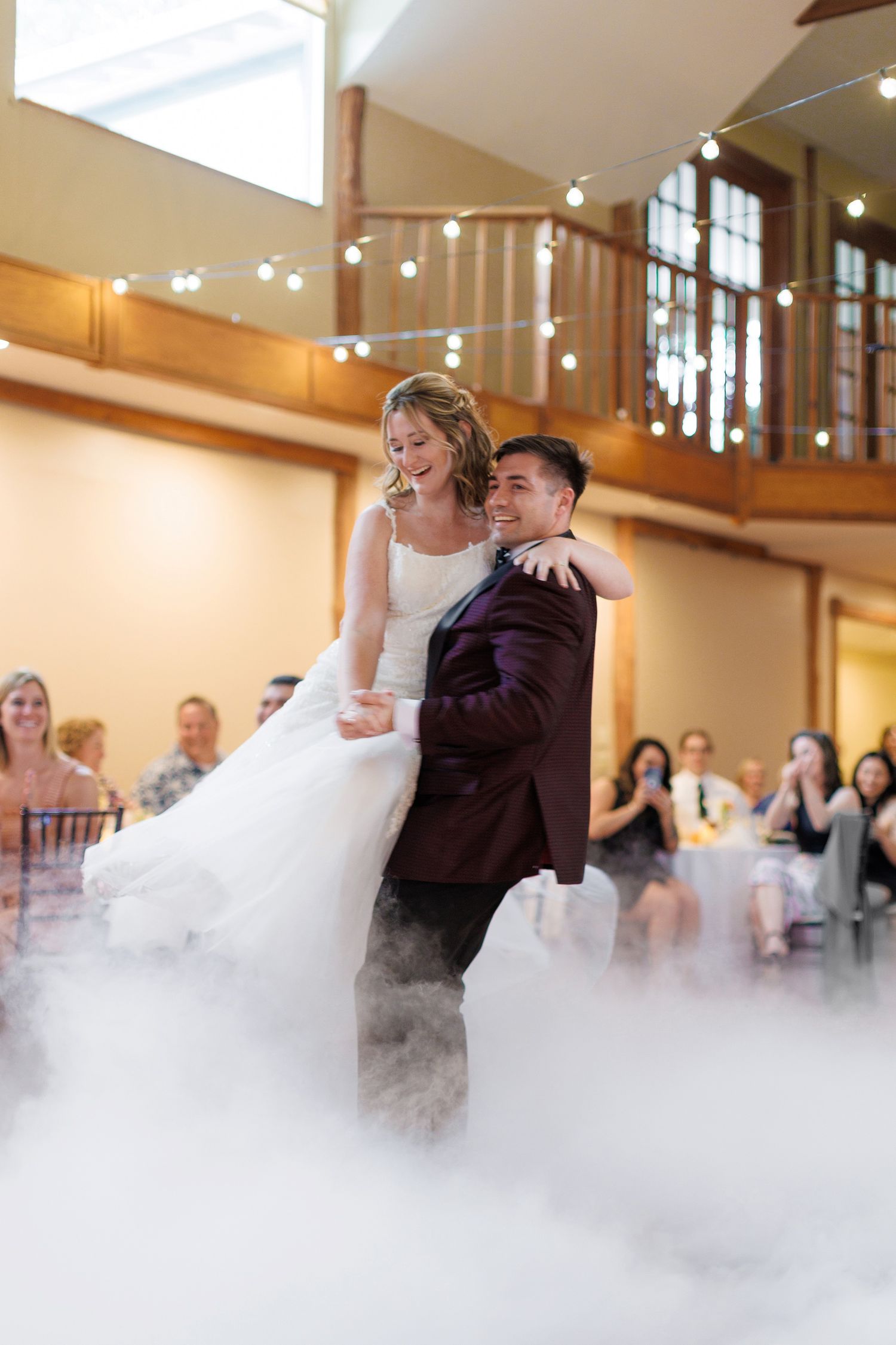 A couple shares their first dance at a wedding reception with dry ice fog creating a dreamy atmosphere.