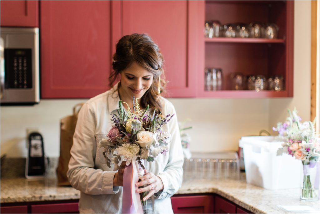 Candid moment with bridal bouquet featuring pink and purple flowers in a kitchen setting.