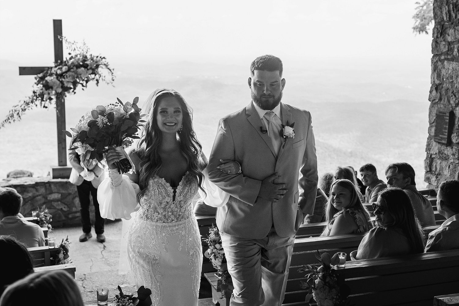 Black and white photo of couple exiting mountain wedding ceremony.