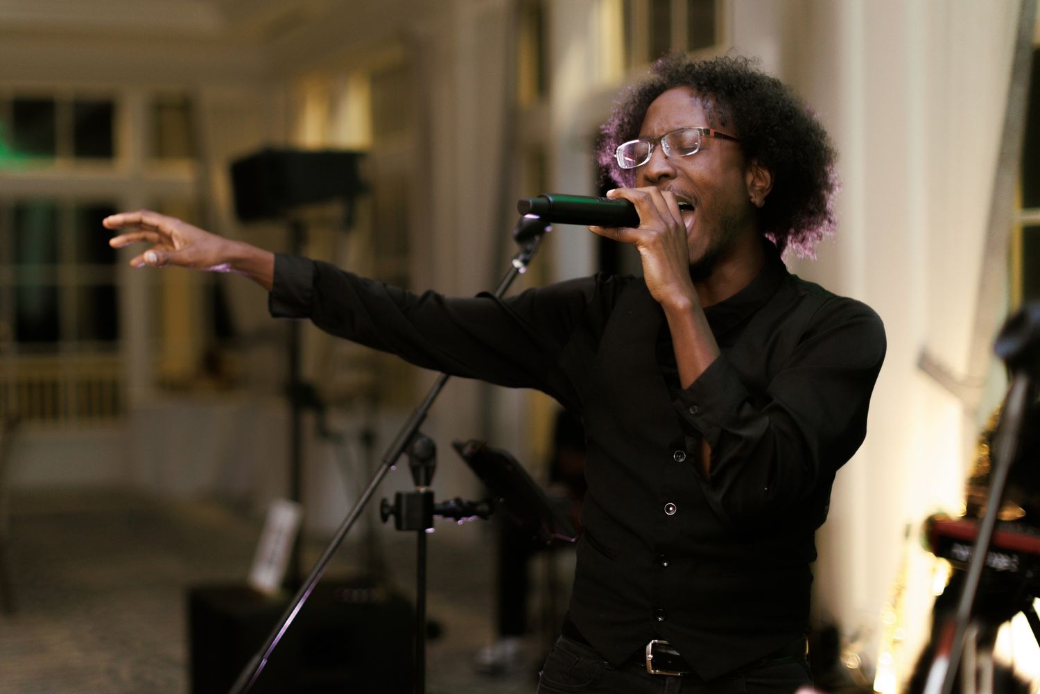 An energetic performer sings passionately into a microphone during an evening event.