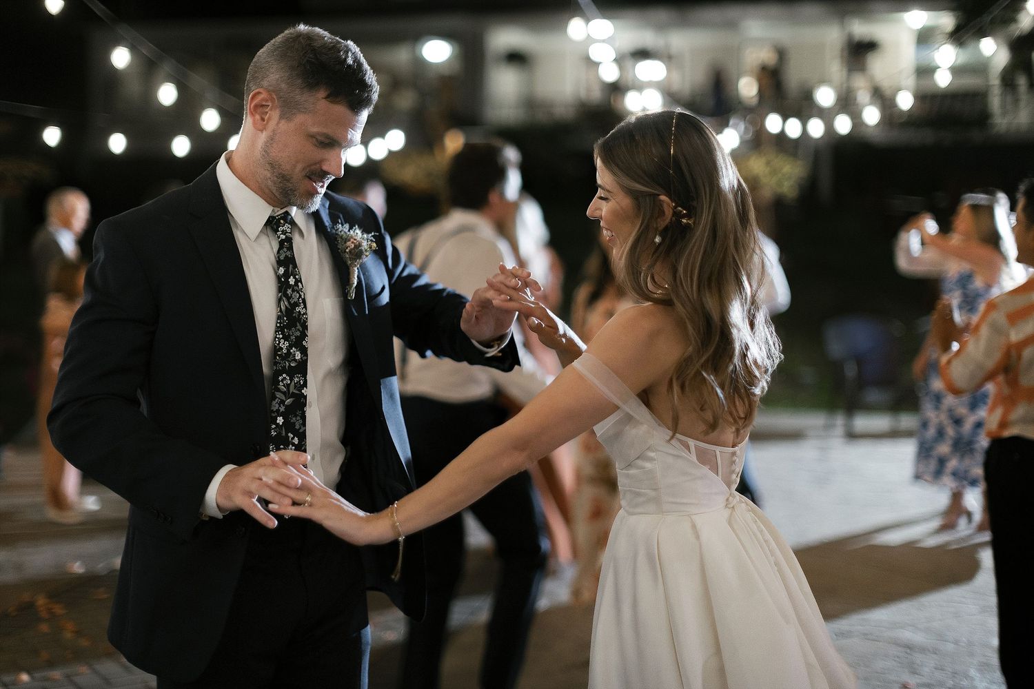 A couple shares a romantic dance moment under twinkling lights at their wedding reception.