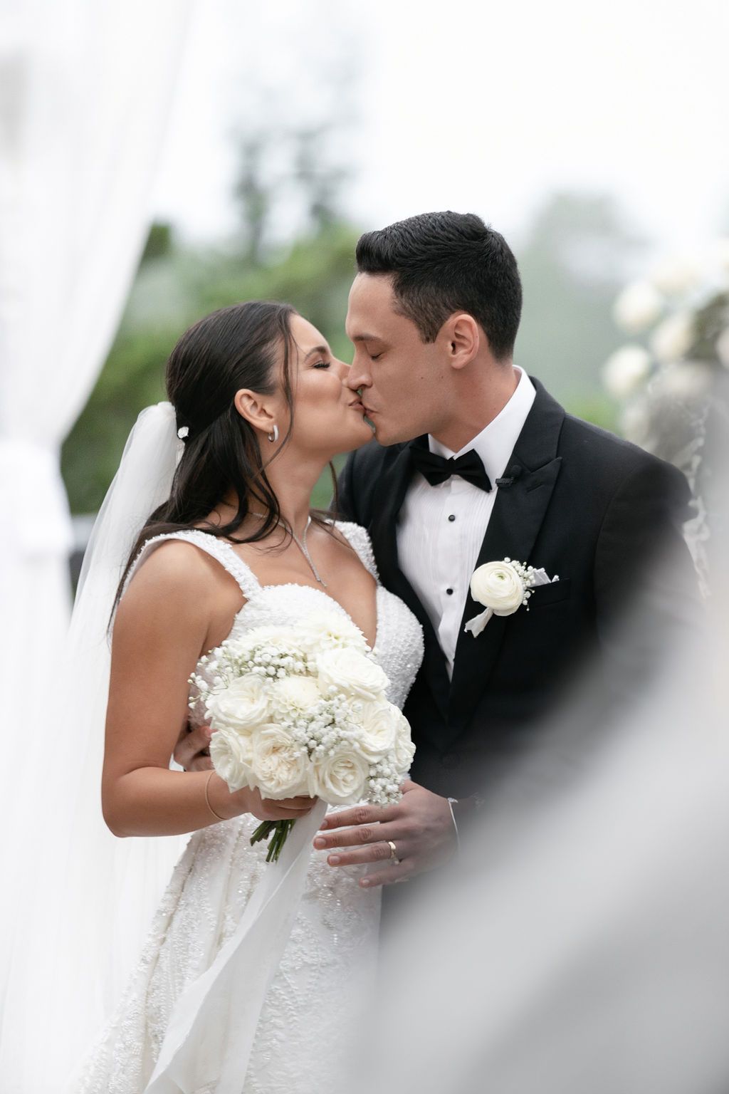 A romantic wedding moment captured with a soft veil effect and white rose bouquet.