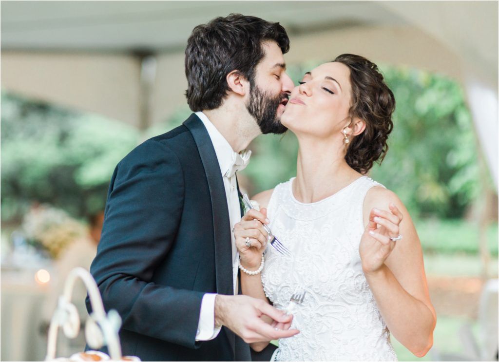 Romantic moment between newlyweds sharing dessert at their outdoor wedding reception.
