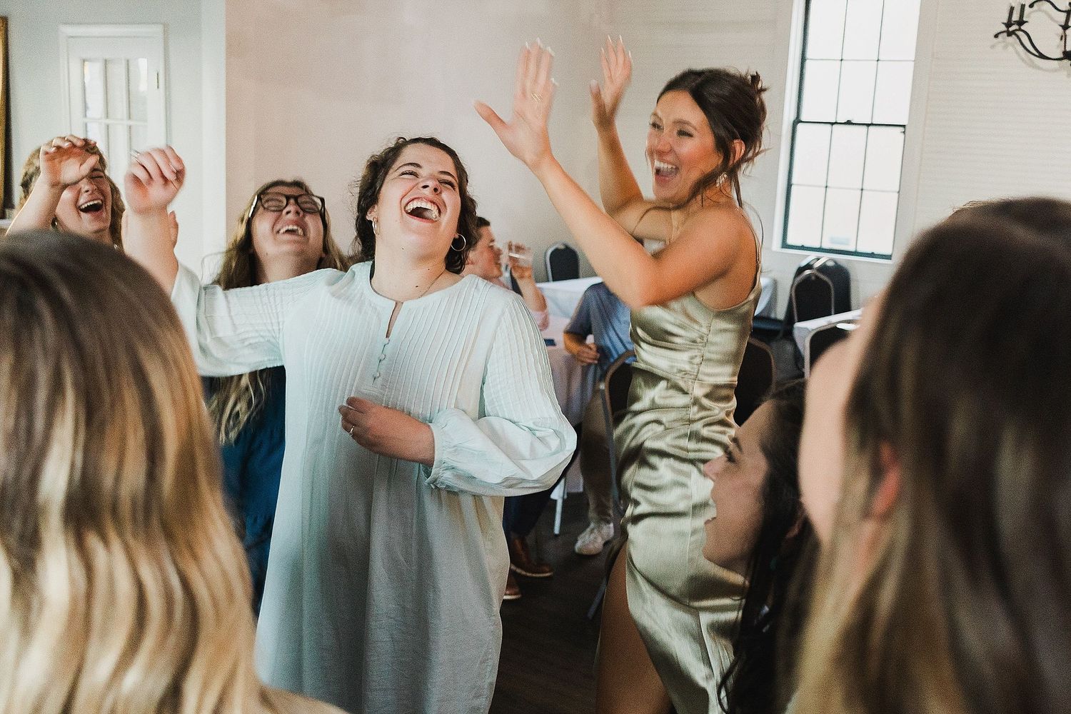 Joyful celebration with guests dancing and laughing at a wedding reception.