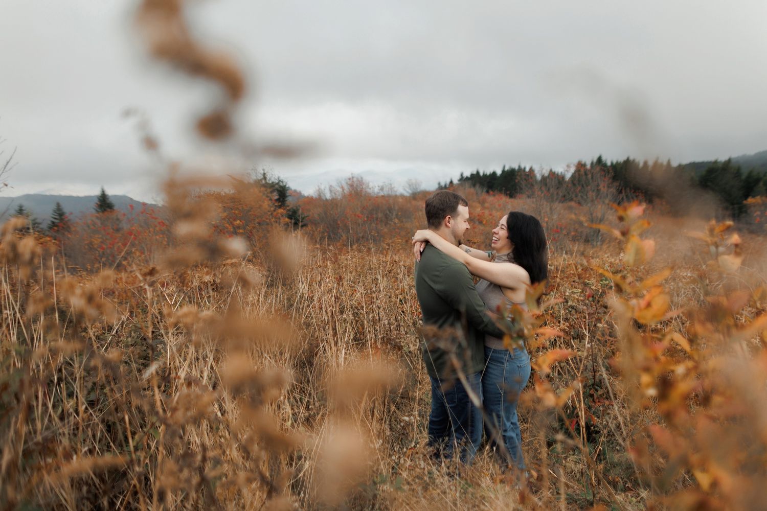 Couple embraces in a golden field of tall grass during autumn sunset creating a romantic silhouette.