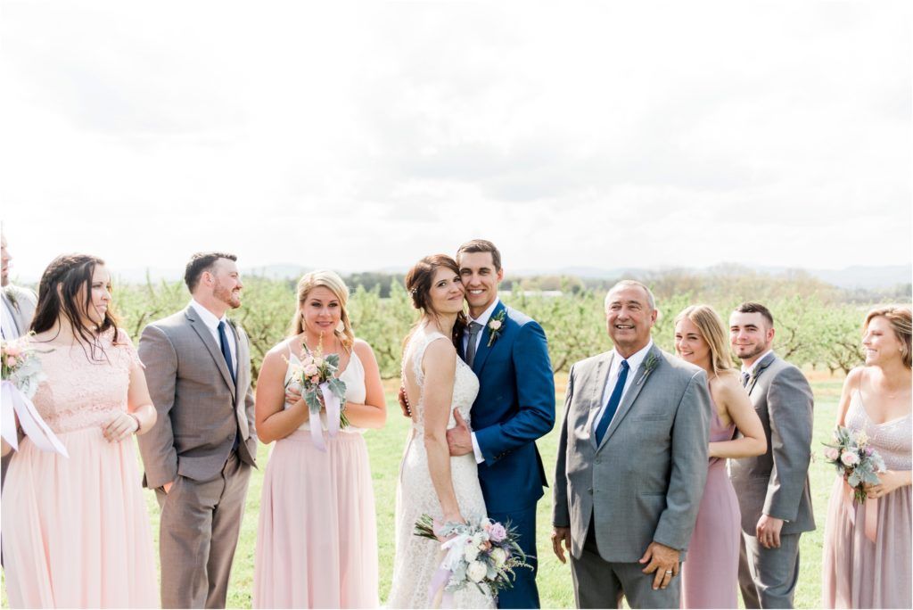 Wedding party in pastel colors celebrating outdoors with joyful expressions.