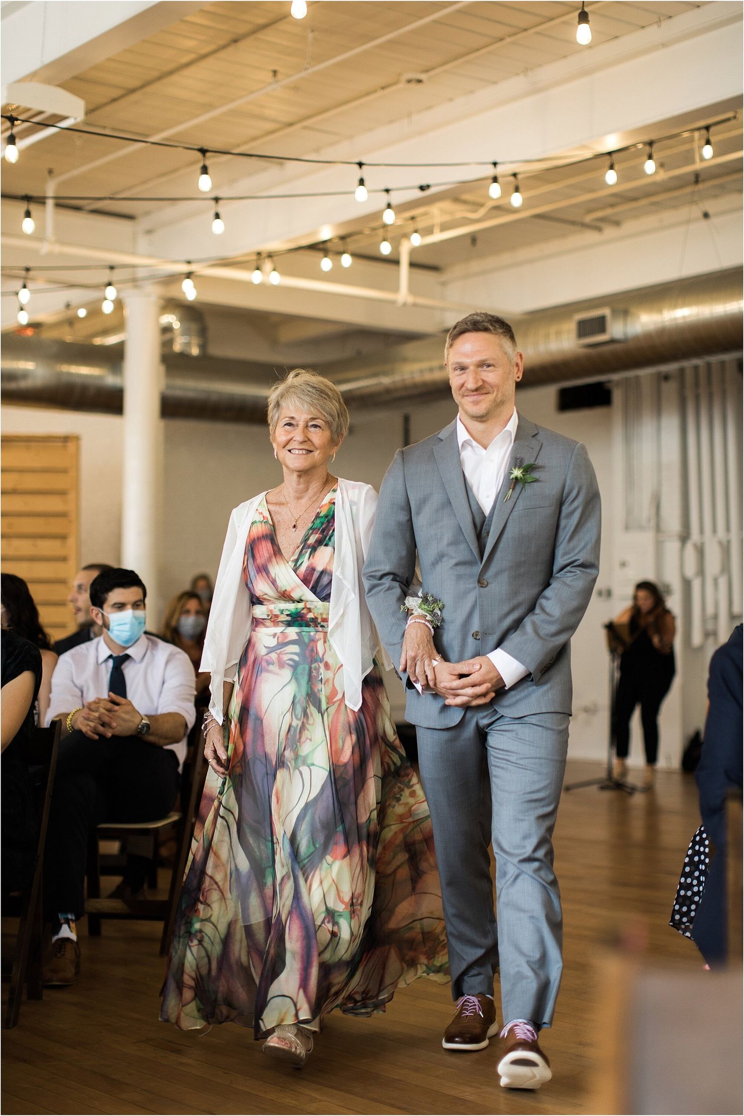 Wedding processional in an indoor venue with string lights and modern decor.