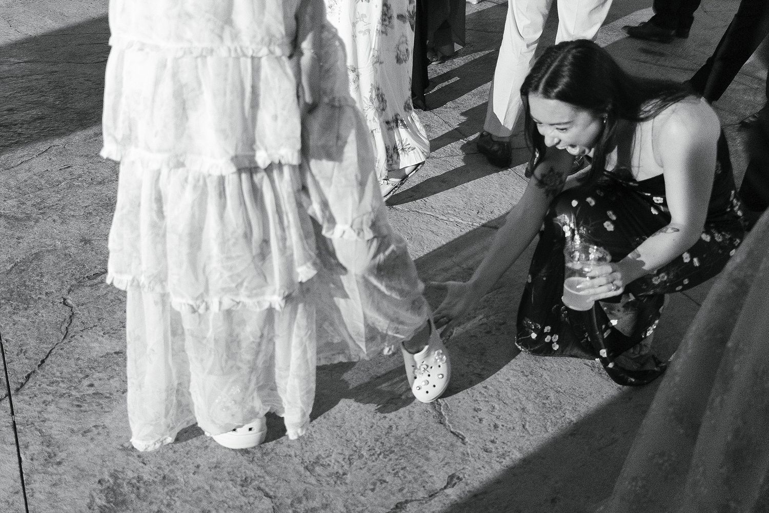Close-up view of wedding dress details and guests' feet on a dance floor.