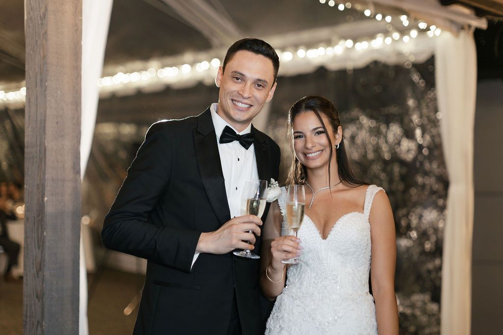 Couple in formal attire toasting with champagne glasses at wedding reception.