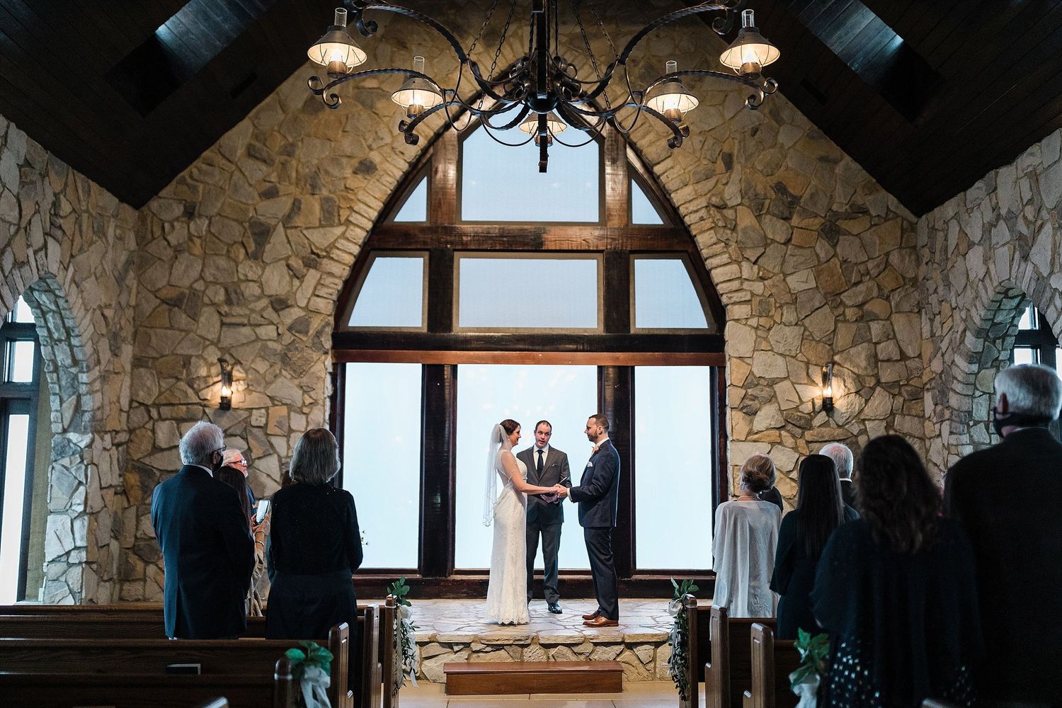 Stone chapel interior with vaulted ceiling and arched windows during an intimate wedding ceremony.
